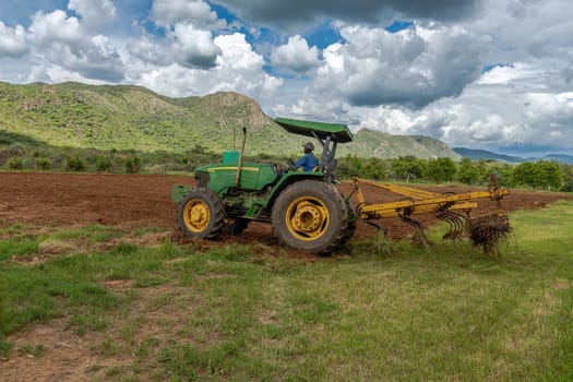 Farmer with green tractor prepares field for sowing, Otavi, Namibia