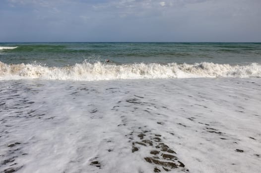 Foamy sea waves on the sandy beach of Bajondillo in Torremolinos, Malaga, Costa del Sol, Spain