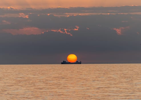 Merchant ship during sunrise over the Mediterranean Sea seen from the beach in Torremolinos. Costa del Sol, Spain