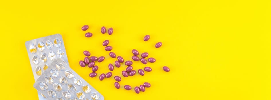 Nutritional supplement purple pills with empty blisters isolated on bold yellow background with copy space. Template for feminine beauty blog social media. Female healthcare concept