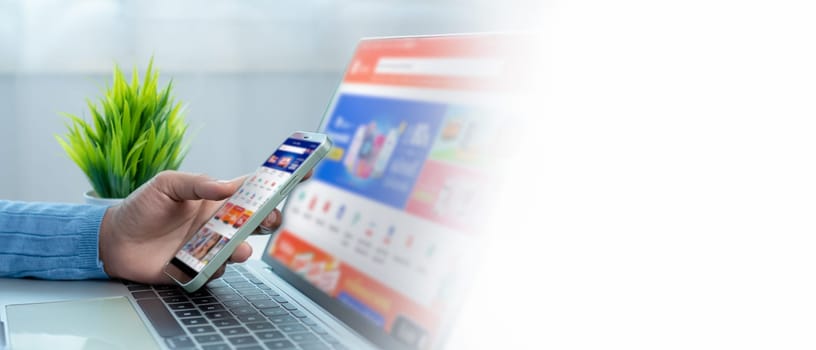 Businesswoman hand with a mobile phone over a laptop, Online shopping on smartphone, Working sitting in office at home, Online shopping and payments, Ecommerce and secure mobile banking concept.