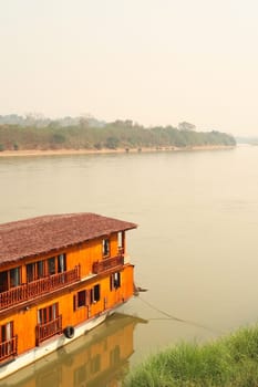 View over the Mekong River with a passenger boat, ship for a Mekong River Cruise docked at the shore in the foreground, Wiang Chiang Kong, Thailand 2023