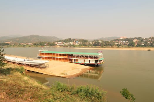Passenger boat, ship for a Mekong River Cruise docked at the shore of the Mekong River in Wiang Chiang Kong, Thailand 2023