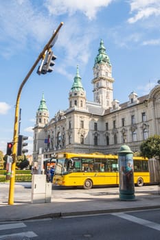Győr, Hungary- September 25 2024: City Hall and yellow bus with people at the bus stop in the street
