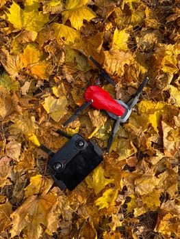 Top view red drone rests on a golden autumn leaves, ready for aerial exploration. Technology and nature concept