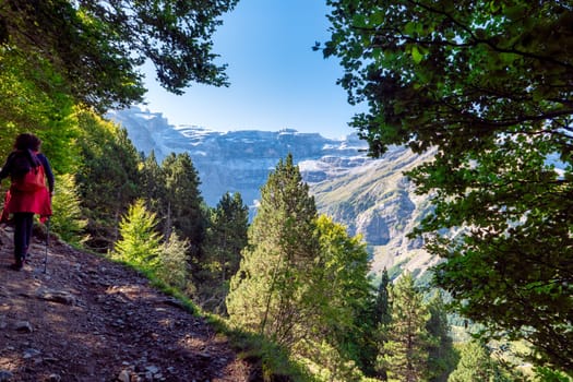 The Cirque of Gavarnie, french Pyrenes mountains. The mountains are covered in snow and the sky is cloudy. The river is surrounded by a lush green valley