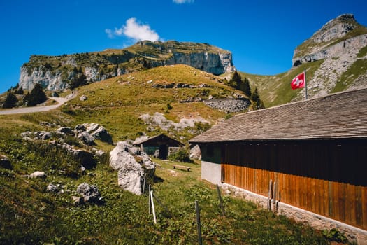 Wooden barn, swiss flag high in Vaud Alps near Leysin on sunny day in summer. Switzerland