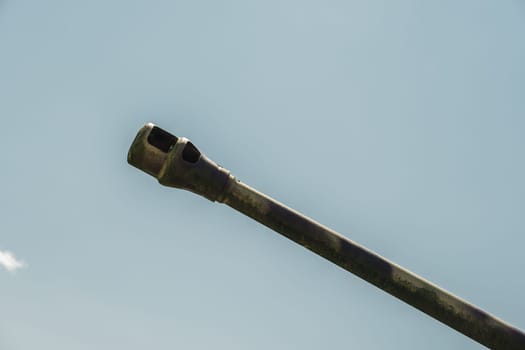 Tank gun barrel shot from below isolated against blue sky close up