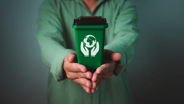 Sustainable living and environmentally friendly habits concept, Man wearing a green shirt holding recycling bin, Concept, Recycle, Waste sorting and sustainability concept, Recycle.