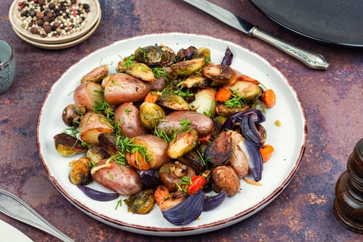 Autumn roasted vegetables. Stewed mushrooms, Brussels sprouts, and potatoes, garnished with onion on a baking dish.