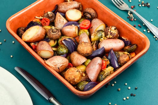 Autumn roasted vegetables. Stewed mushrooms, Brussels sprouts, and potatoes, garnished with onion on a baking dish.