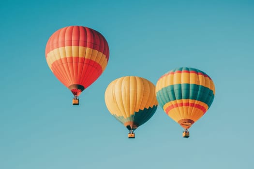 Three vibrant hot air balloons floating in a bright blue sky on a sunny day.