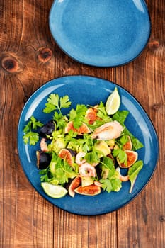 Platter of green salad with figs and figs. Seafood salad.