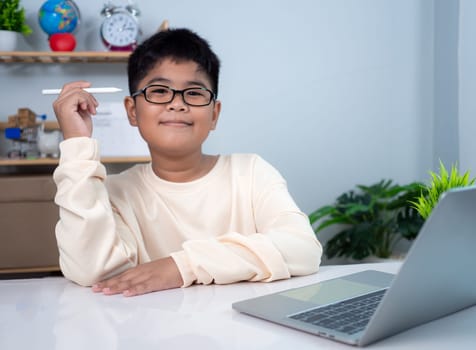 Little Asian boy student using computer laptop learning. Educational of tech concept, Staying at home, Presenting a modern educational way of life. Virtual internet online class from school teacher.