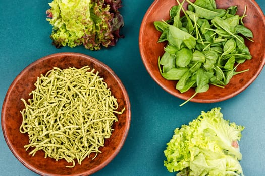 Vibrant green spinach or spinach pasta with fresh spinach leaves on wooden table. Culinary recepies, healthy food, fitness, diet.