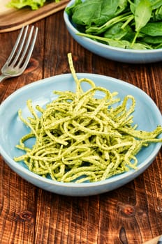 Vibrant green spinach or spinach pasta with fresh spinach leaves on wooden table. Culinary recepies, healthy food, fitness, diet.