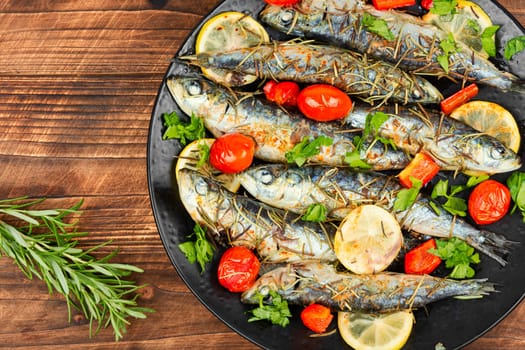 Sardines roasted with cherry tomatoes rosemary and lemon on table.