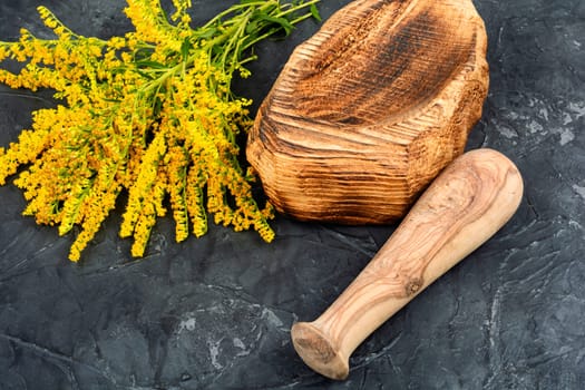 Medicinal herbs and vintage wooden mortar on a rustic wooden table.