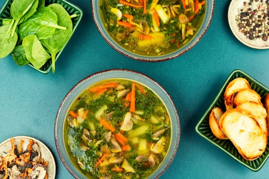Homemade thick vegetarian mushroom soup with spinach and vegetables in a ceramic bowl. Copy space.