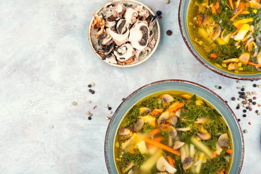 Homemade thick vegetarian mushroom soup with spinach and vegetables in a ceramic bowl. Copy space.