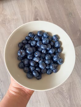 Fresh blueberries in white plate close-up, background.
