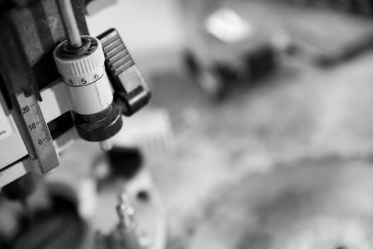 Adjusting the settings on a precision tool in a workshop, with a shallow depth of field. - black n white -