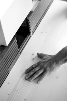 Carpenter is checking the smoothness of wooden planks in his workshop, ensuring high quality craftsmanship. - black n white -