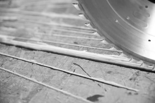 Circular saw cutting a wood plank in a carpentry workshop, with sawdust on the work surface. - black n white -