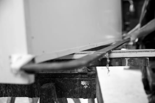 Carpenter is using traditional hand tools to build a large wooden structure in a workshop. - black n white -