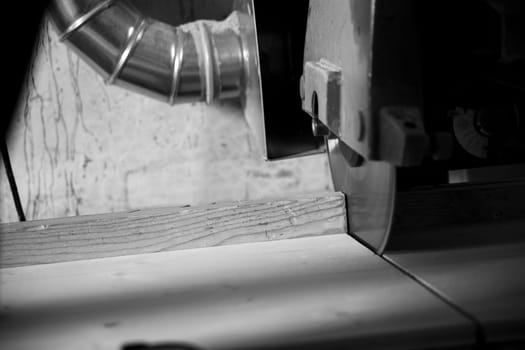Skilled carpenter cutting wood with a circular saw in a busy workshop. Sawdust flies as the blade slices through the timber, highlighting the beauty of the craft. - black n white -