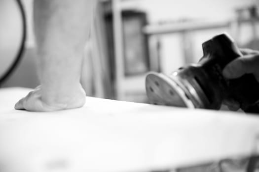 Skilled carpenter sanding wooden plank with electric sander in cozy workshop, creating smooth finish with precision and dedication. - black n white -