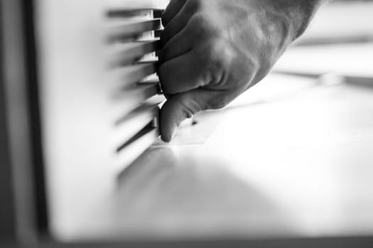 Carpenter is carefully positioning a piece of wood on a workbench, using his hand to ensure accuracy. - black n white -