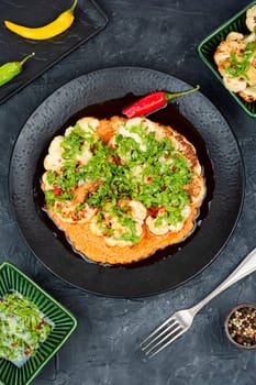 Fried cauliflower, golden roasted cauliflower florets garnished with fresh herbs. Top view.