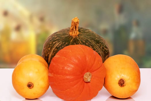 Pile of pumpkins. Close-up of a stack decorative colorful pumpkins on a bright table against abstract blurred natural grocery shop background. Space for design.