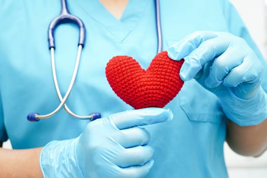 Asian woman doctor holding red heart for health in hospital.
