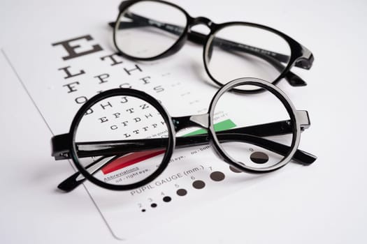 Glasses on eye exam chart to test eyesight accuracy of reading.
