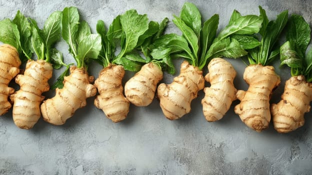 A row of fresh ginger roots displaying their earthy texture and vibrant green leaves arranged neatly on a rustic surface.