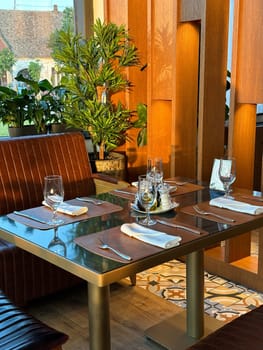 Cozy restaurant interior with elegantly set table, ready for guests. the warmth of the wooden accents and green plants create a welcoming atmosphere