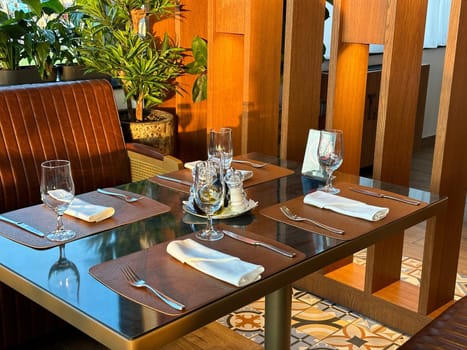 Cozy restaurant interior with elegantly set table, ready for guests. the warmth of the wooden accents and green plants create a welcoming atmosphere