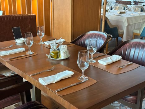 Cozy restaurant interior with elegantly set table, ready for guests. the warmth of the wooden accents and green plants create a welcoming atmosphere