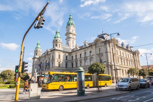 Gyor, Hungary- September 25 2024: City Hall and yellow bus with people at the bus stop in the street