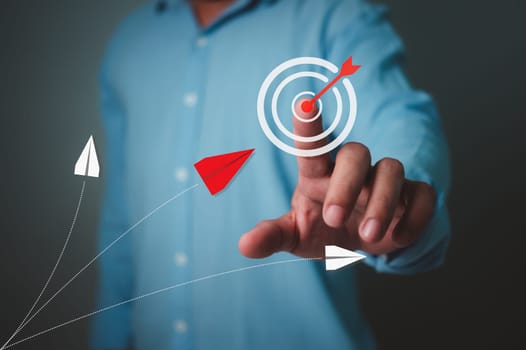 Businessman pointing finger at target icons while red paper airplane flying towards the target, Business target or goal success and winner concept, Goal setting, Strategic planning for business growth