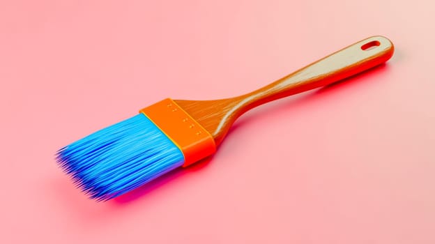 Vibrant blue paint brush with orange and wooden accents on pink background, exuding creativity and renovation potential for any project