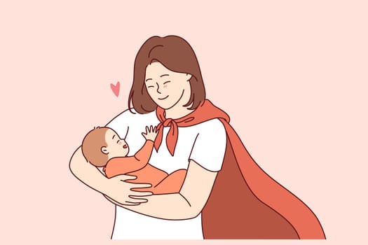Supermom in red hero cape holds happy baby, smiling and rejoicing at birth of long-awaited son. Supermom with baby in arms, proud of motherhood and opportunity to give life to new human