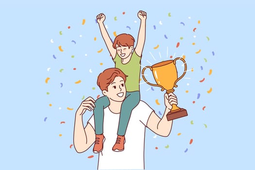 Dad with champion trophy and son sitting on podium celebrates father day and is proud of having heir. Young man received award for best father of year for success in raising child.