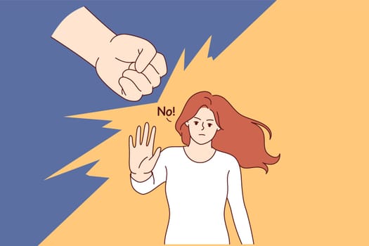 Woman says no to domestic violence and makes stop gesture, standing near fist of wants to strike. Girl resists domestic violence, wanting to get rid of toxic relationships and beatings