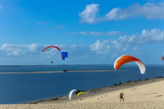 Dune of Pilat, France - August 14, 2024: People paragliding at the Great Dune of Pilat, Arcachon Basin, Nouvelle Aquitaine, France.