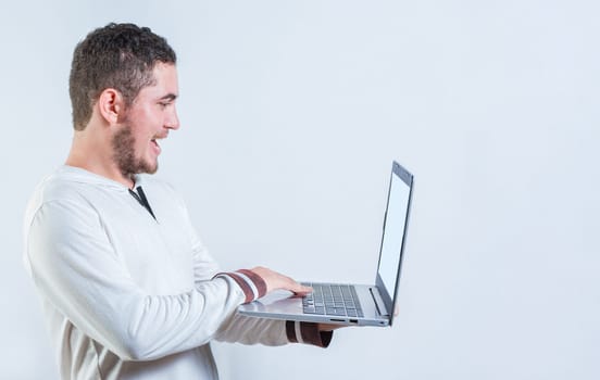 Portrait of happy young man standing using laptop isolated. Excited guy holding and looking at an promotion on laptop screen