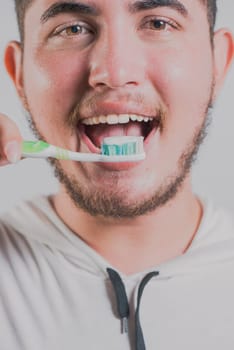 Smiling man brushing teeth isolated. Health and tooth brushing concept