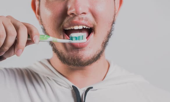 Health and tooth brushing concept. Smiling man brushing teeth isolated